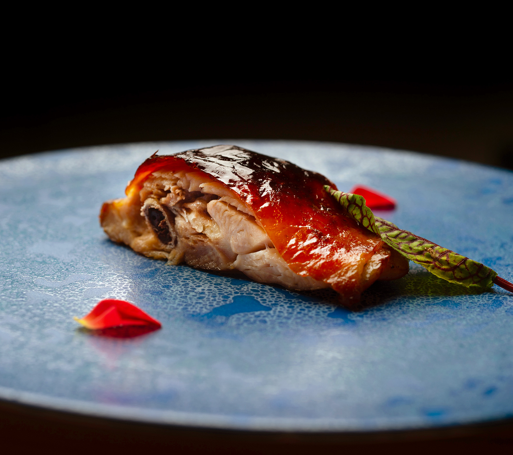 青い皿に華やかに盛り付けられた「地鶏のパリパリ焼き」